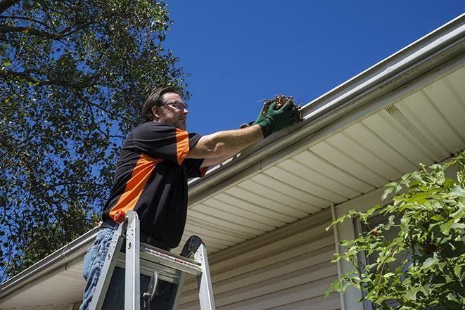 roofing technician replacing a rusted and leaking gutter in Artesia, CA